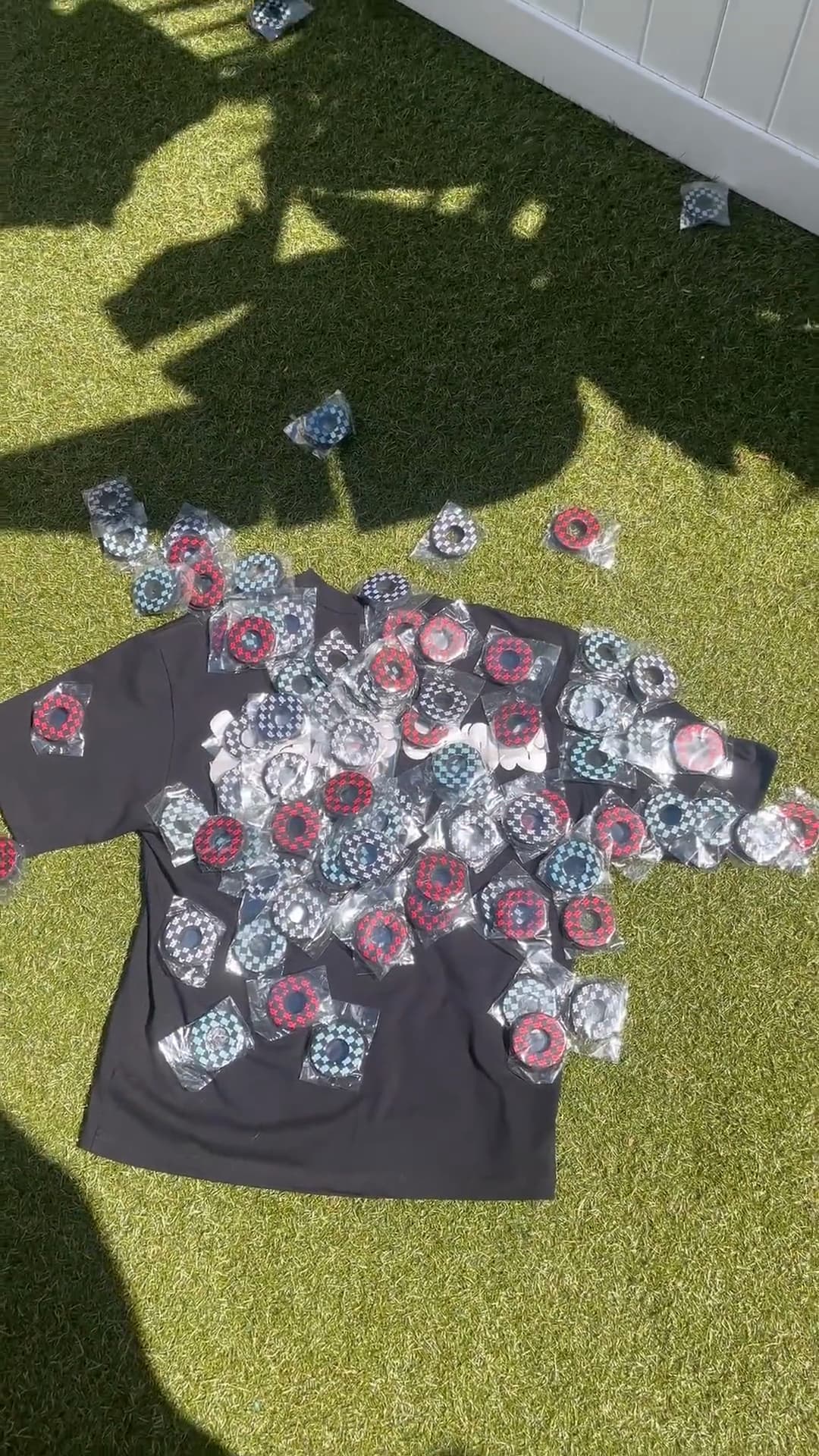 The Puff Print Tee on the grass with grip donuts and keychains tipped over it